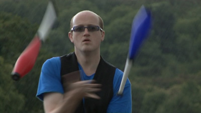 A still from my Video Showreel showing me club juggling on a very wet day on the Auld Brig in Stirling